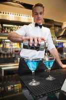 Bartender pouring cocktail into glasses