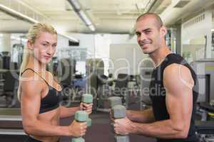 Couple exercising with dumbbells in gym