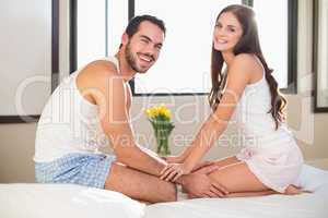 Young couple smiling at camera in bed