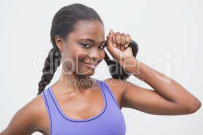 Fit woman smiling at camera holding kettlebell