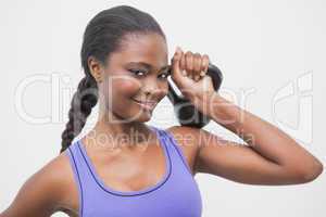 Fit woman smiling at camera holding kettlebell