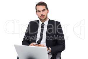 Cheerful businessman with laptop using smartphone