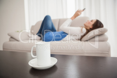 Pretty brunette sending a text on the couch