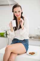 Pretty brunette holding a mug and cookie