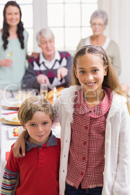 Brother and sister smiling at camera in front of their family