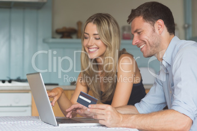 Cute couple using laptop together to shop online