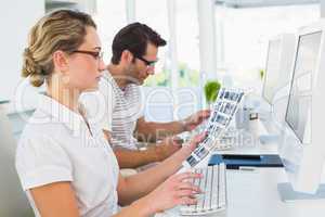 Blonde editor looking at contact sheet at her desk