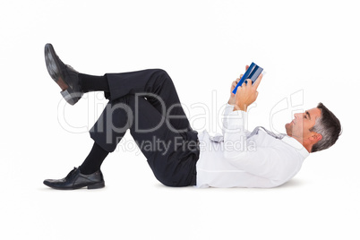 Concentrated businessman lying and reading a book