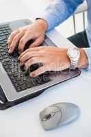 Close up of hands with wrist watch typing on laptop