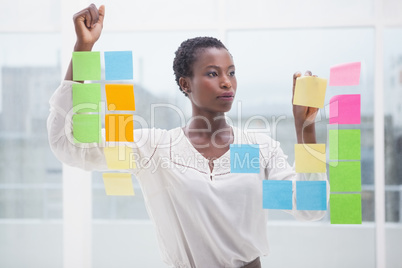 Creative businesswoman writing on sticky notes on window