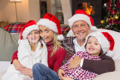 Festive family in santa hat hugging on couch