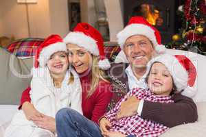 Festive family in santa hat hugging on couch