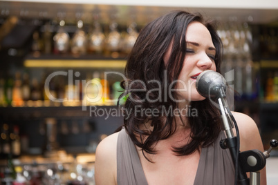 Brunette haired woman singing in a microphone