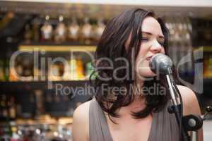 Brunette haired woman singing in a microphone