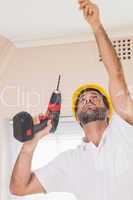 Construction worker drilling hole in ceiling