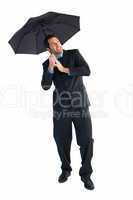 Businessman standing under black umbrella