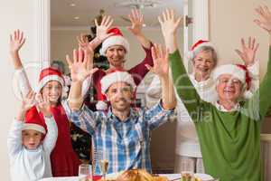 Happy extended family in santa hat cheering at camera