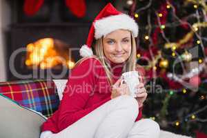 Smiling blonde holding a mug of hot chocolate at christmas