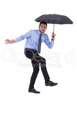 Anxious businessman under umbrella balancing