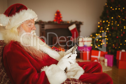 Concentrated santa using smartphone at christmas