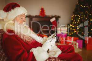 Concentrated santa using smartphone at christmas