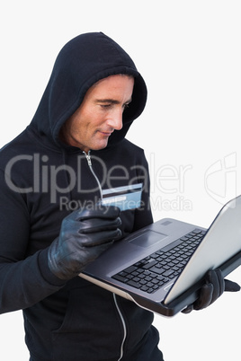 Smiling thief in hood jacket using laptop and credit card