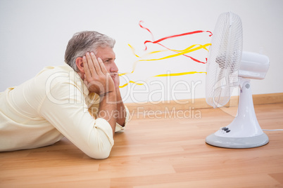 Man lying on floor looking at fan