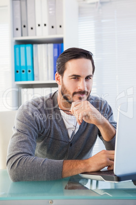 Casual businessman using his laptop at his desk