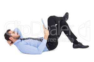 Businessman lying on floor using tablet