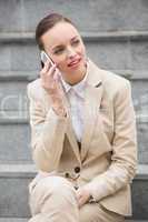 Young businesswoman sitting on steps on the phone