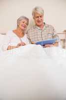 Senior couple relaxing in bed using tablet pc