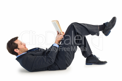 Businessman lying on the floor while reading a book