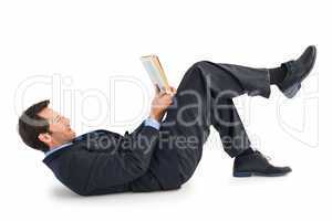 Businessman lying on the floor while reading a book