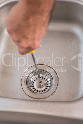 Man fixing sink with screwdriver