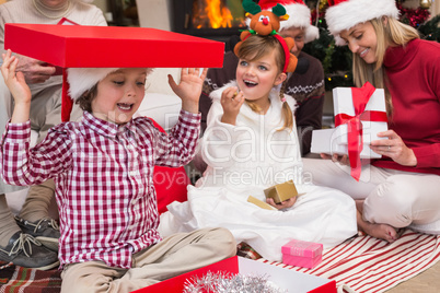 Son playing with a gift sitting on the floor with his family