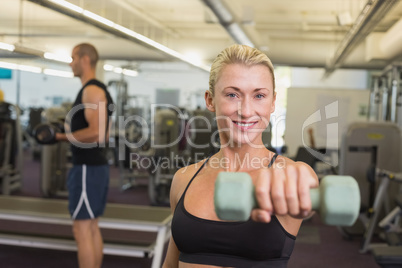 Couple exercising with dumbbells in gym