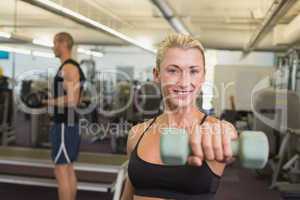Couple exercising with dumbbells in gym