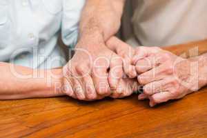 Senior couple holding hands on table