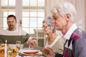 Family saying grace before christmas dinner