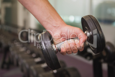 Fit man lifting heavy black dumbbell