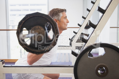 Fit man lifting heavy barbell