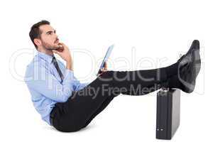 Businessman sitting with feet on his briefcase thinking