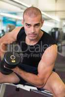 Portrait of man exercising with dumbbell in gym