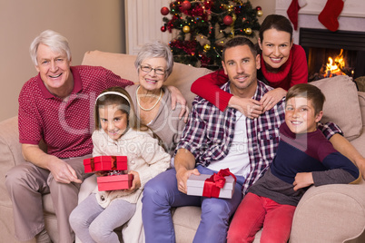 Multi generation family holding gifts on sofa