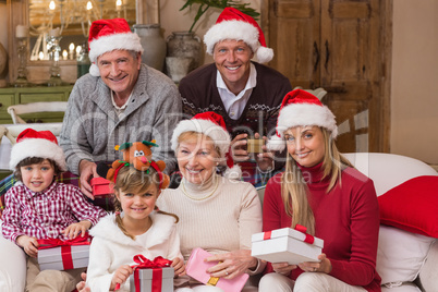 Portrait of a happy extended family in santa hat holding gifts