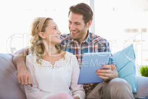Couple using tablet pc while looking at each other
