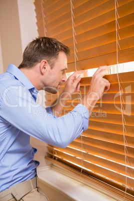 Curious man looking through the blinds