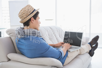 Young creative man using laptop on couch