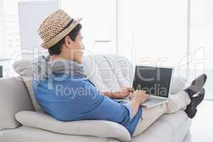 Young creative man using laptop on couch
