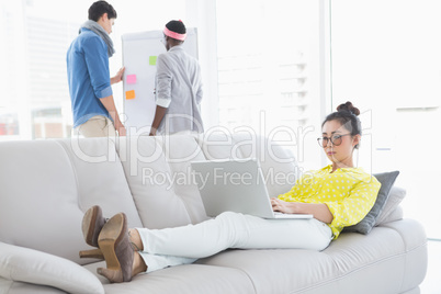 Young creative woman using laptop on couch